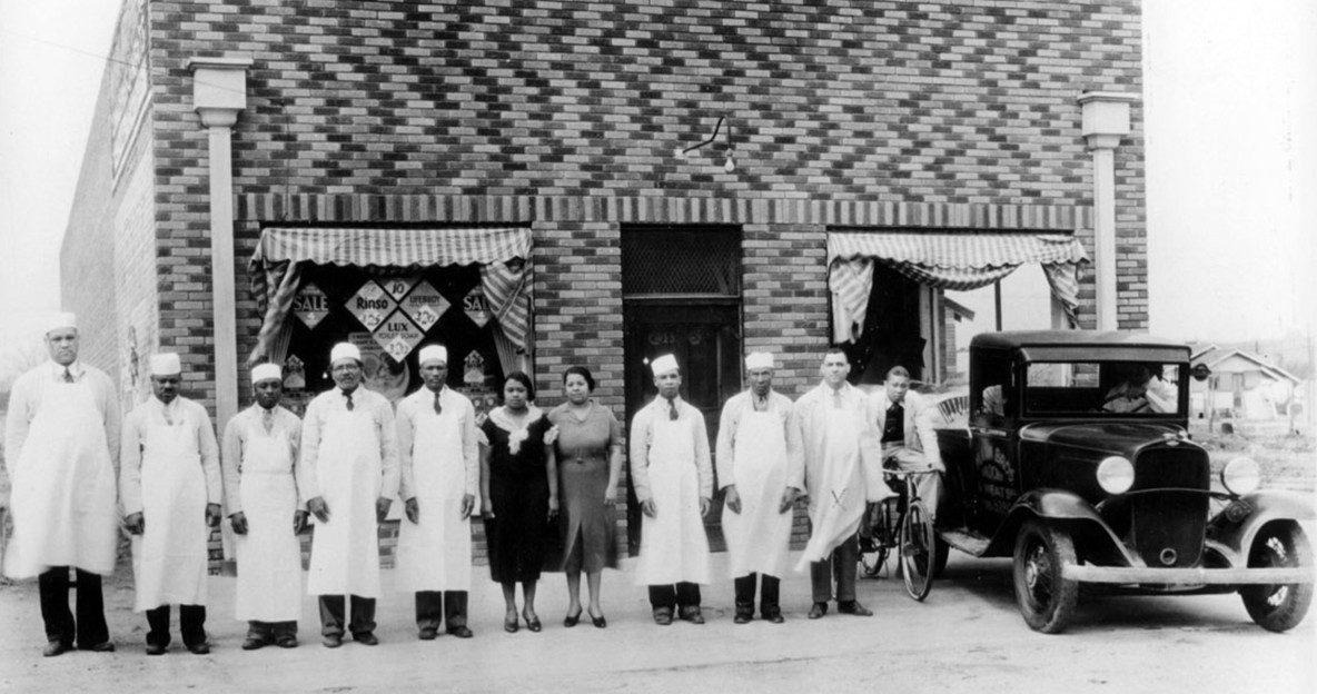 A group of people standing in front of a brick building with patterned walls.
